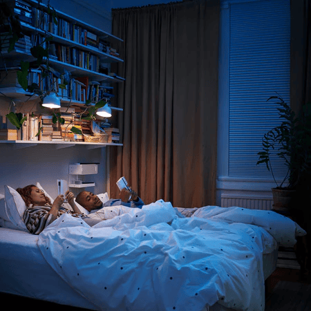 People in bed with some lights on illuminating the dark room