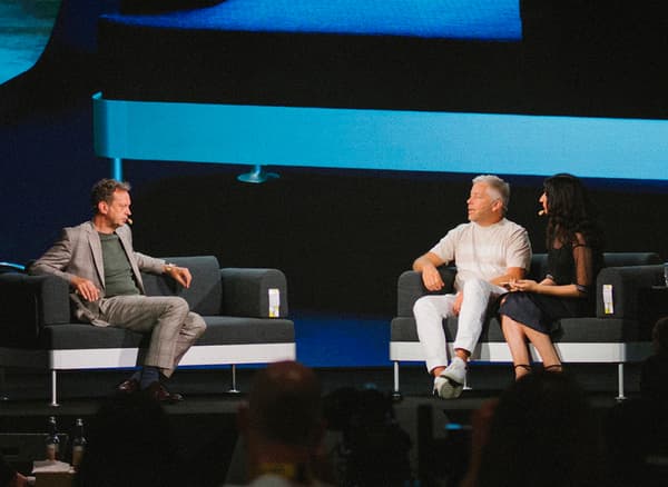 People on a stage with a sofa on the screen behind them.