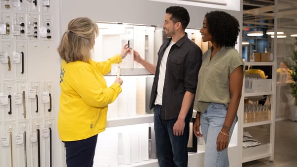 People review cabinet door styles and hardware displays in an IKEA showroom.