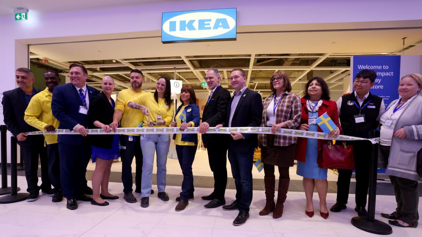 People standing in front of an IKEA store cutting a ribbon