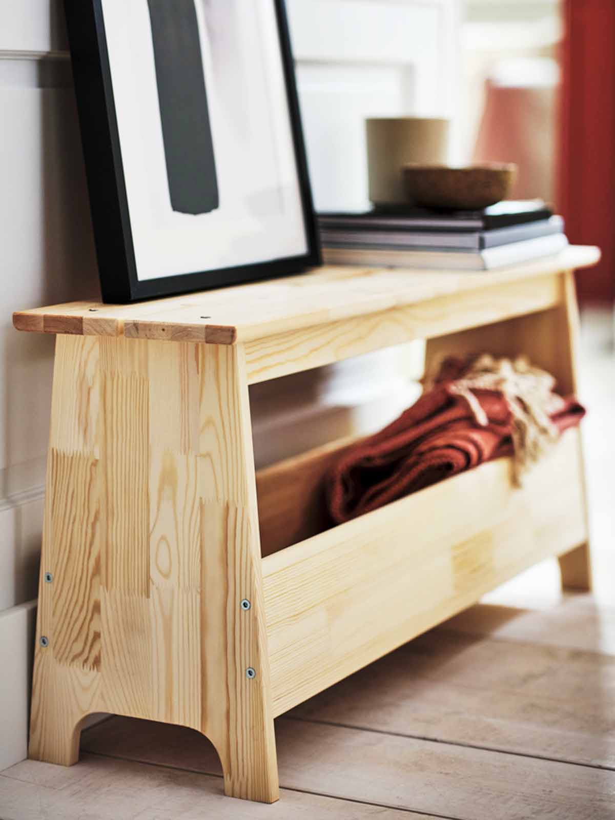PERJOHAN bench in the living room filled with various belongings, with several books and a photo frame stacked on top of it.