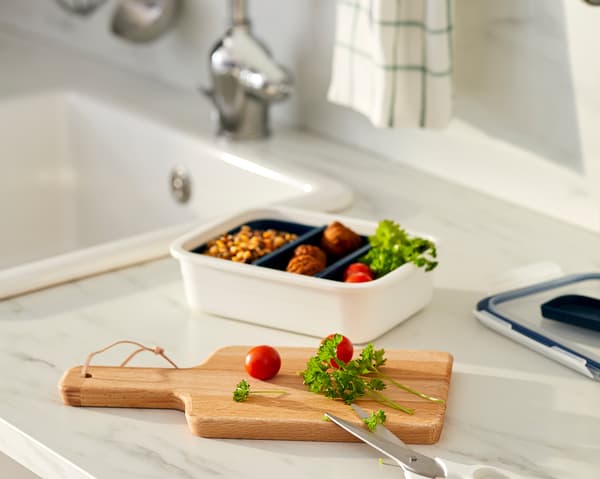 Permukaan atas kerja dapur dengan hidangan dibahagikan kepada beberapa petak kotak makan tengah hari, landas cencang dengan tomato dan pokok herba yang baru dipotong.