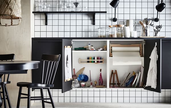 Permukaan atas kerja dengan dua pintu almari di bawahnya terbuka, mendedahkan studio seni miniatur yang lengkap tersorok di dalamnya.