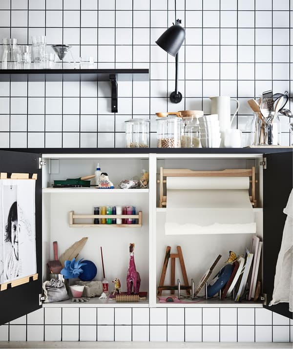 Permukaan atas kerja dengan dua pintu almari di bawahnya terbuka, mendedahkan studio seni miniatur yang lengkap tersorok di dalamnya.