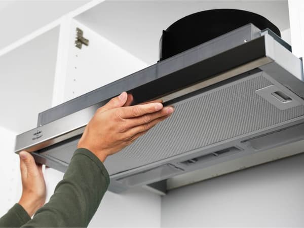 Person adjusting extractor fan in the kitchen 