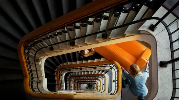 person carrying sofa down stairs