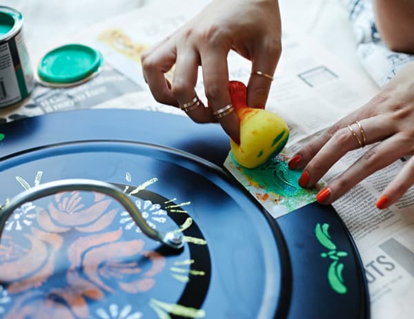 Person decorating a dustbin lid.