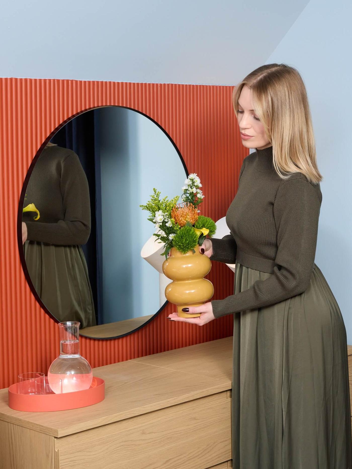 Person holdig a vase next to a mirror
