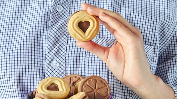 Person holding a cookie with a heart-shaped cutout in the center