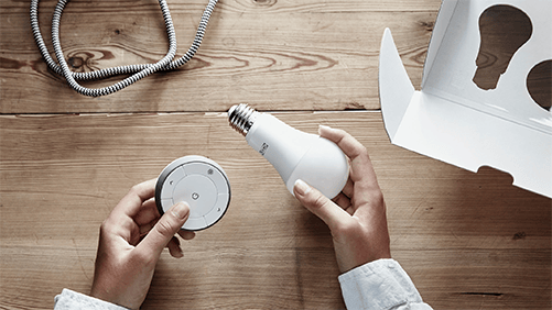 Person holding TRÅDFRI dimming kit consisting of an LED bulb and a remote control.