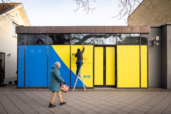 Person på stege som klär en fasad i gult och blått.