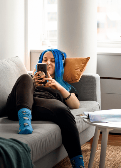 Person reclinging on a sofa whilst on their phone and smiling