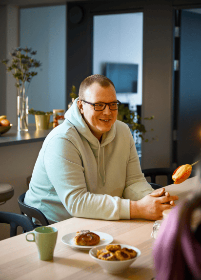 Person sat in a break area net to blue mug and bowls of food smiling at someone