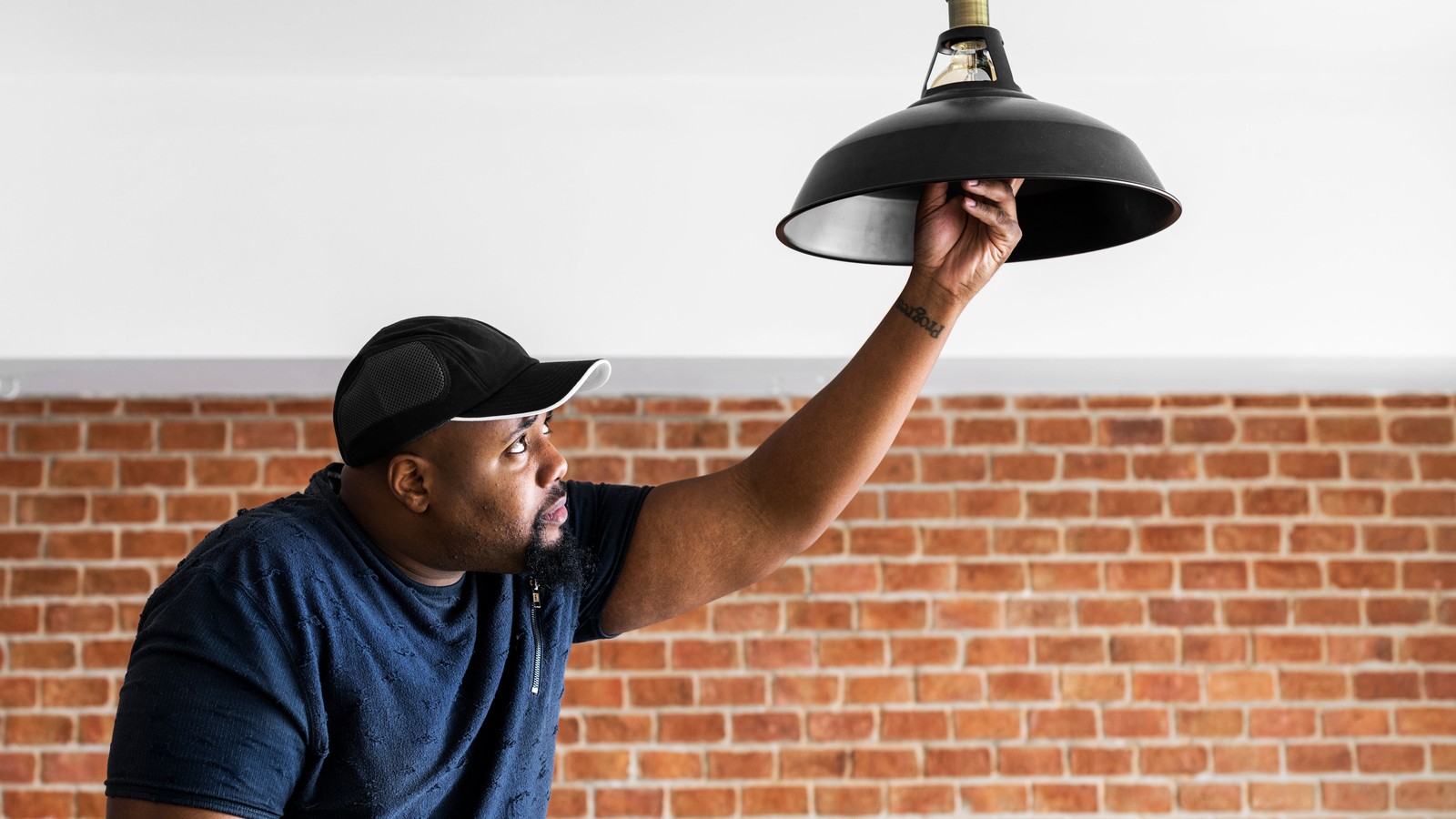 Person screwing in a lightbulb on a pendant lamp