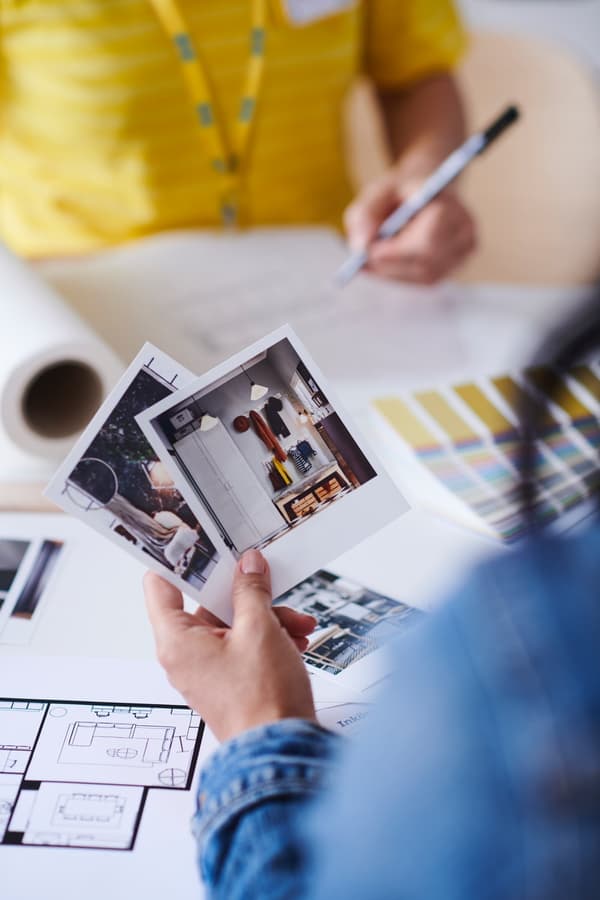 Person showing interior photos while reviewing floor plans and color samples in an IKEA planning space.