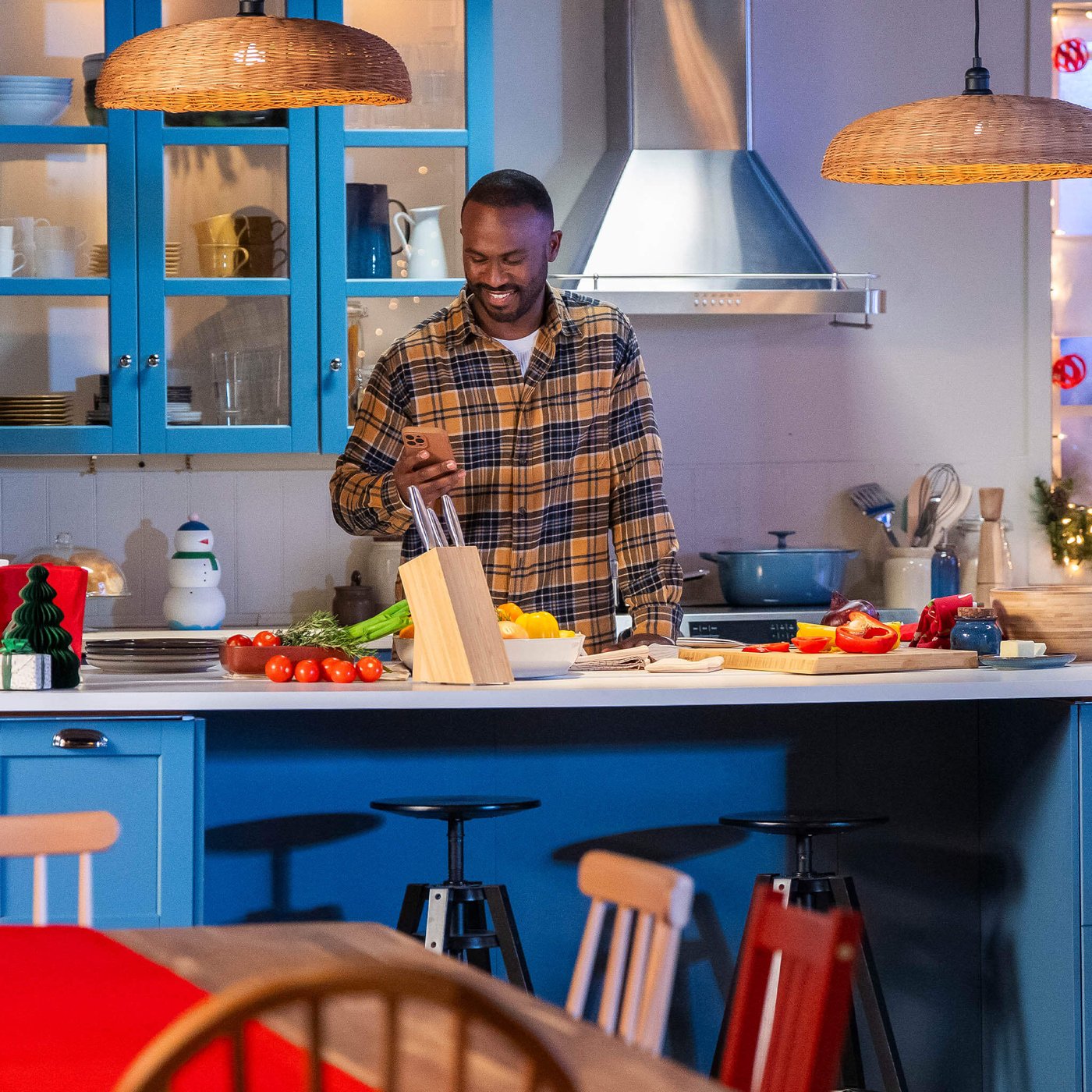 Person standing in a modern kitchen with blue cabinets, preparing vegetables on a counter with cutting boards and utensils.