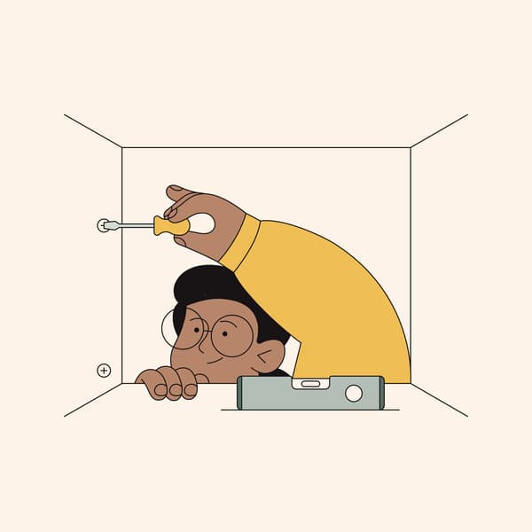 Person with glasses using screwdriver on wall, in a small space with level tool in the foreground.