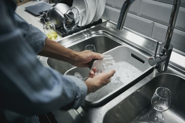 Persona lavando copas en un lavadero ahorrando agua. 