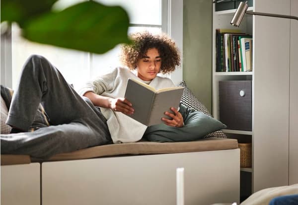 Persona leyendo libro con lámpara RYET apuntando a su cuento mientras está acostada en la cama.