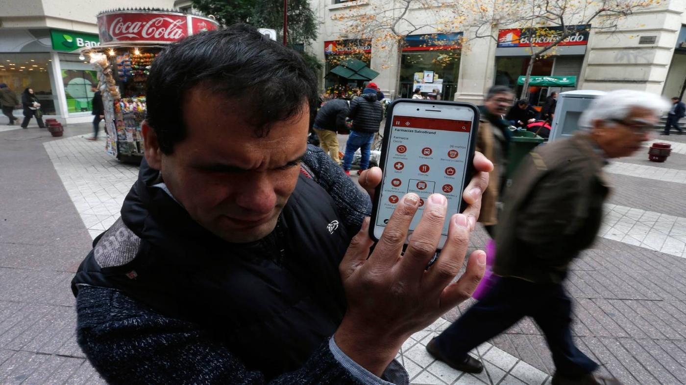 Persona no vidente usando la aplicación con sus manos, caminando por las calles de Santiago.