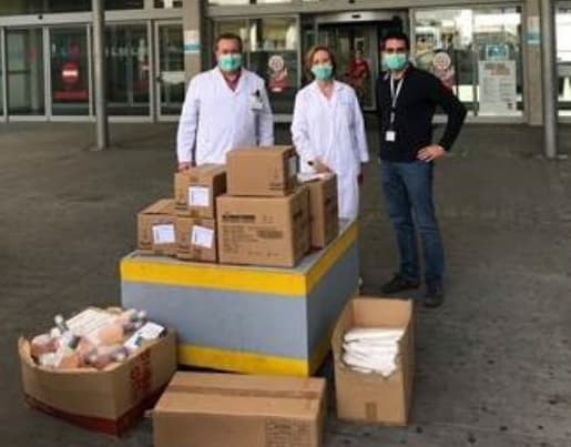 Personal mèdic posant al costat d’una gran quantitat de caixes amb donacions d’IKEA, en un espai de recollida solidària.