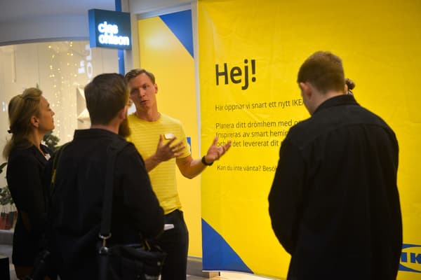 Personer framför en gul fasad som står och pratar