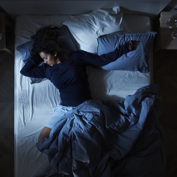 Personne dormant dans un lit  la parure bleu dans la pénombre
