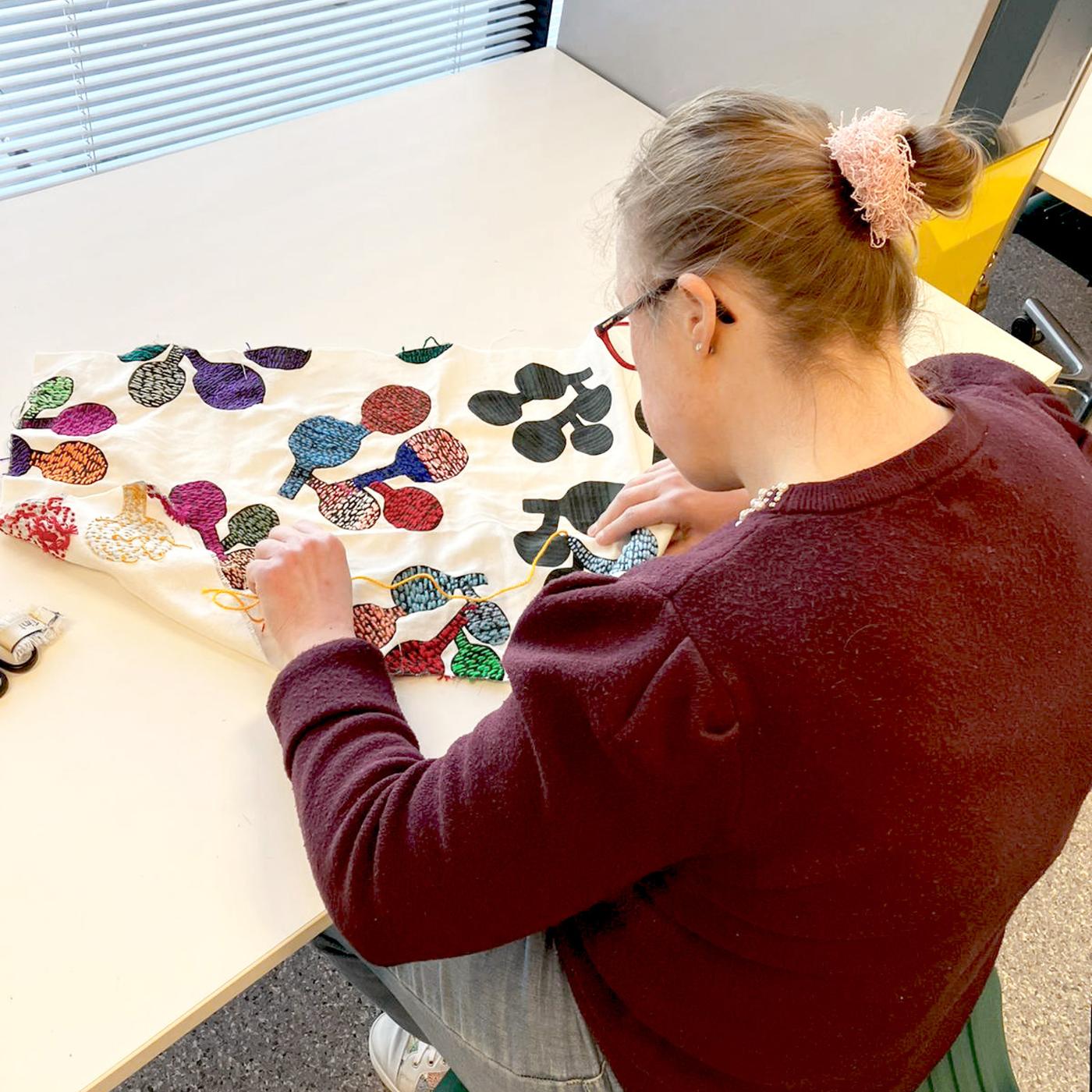 Persoon die textiel bewerkt.