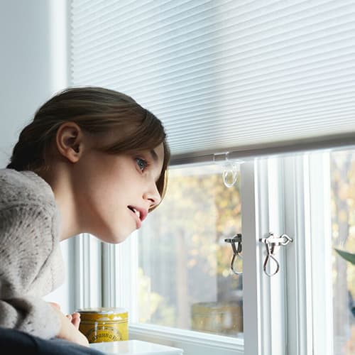 Persoon die uit zijn raam naar buiten kijkt.