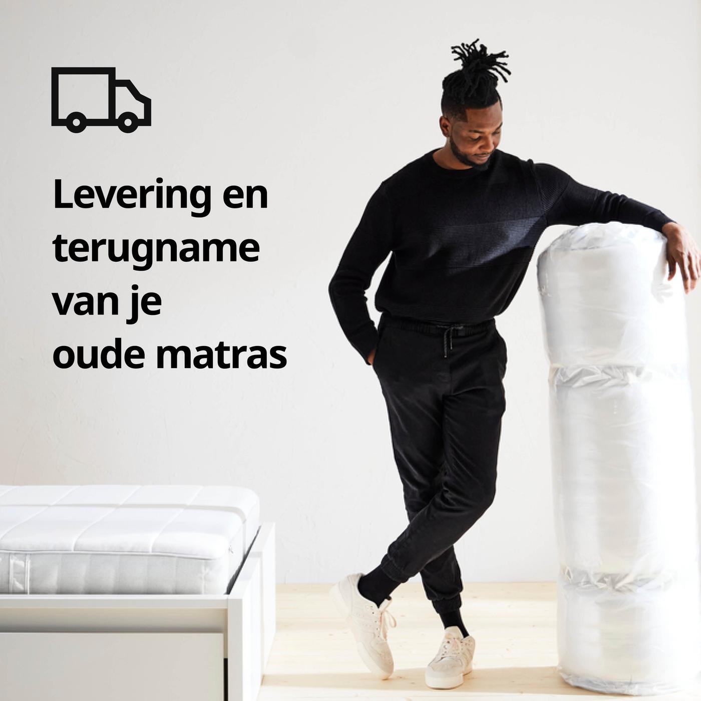 Persoon leunt tegen opgerolde matras in witte kamer; links een bed met matras en op de afbeelding de tekst "Levering en terugname van je oude matras" met vrachtwagenpictogram.