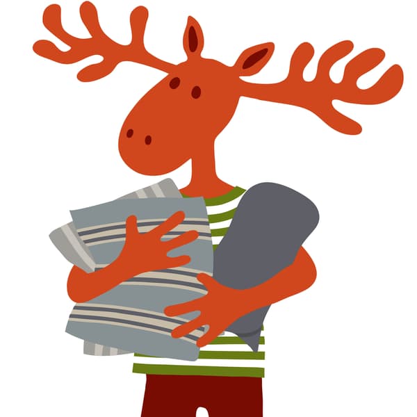 Peták, amint egy díszpárnát és egy takarót tart.