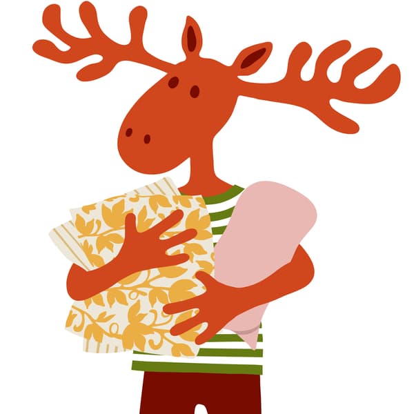 Peták jávorszarvas díszpárnákat és egy takarót tart a kezében.