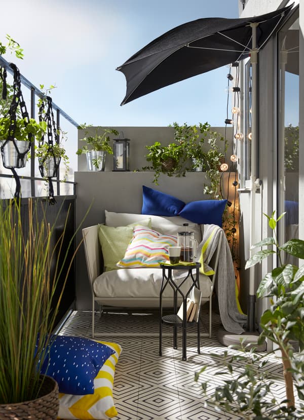Petit balcon confortable en beige, bleu et gris, avec fauteuil intérieur/extérieur HAVSTEN en beige.