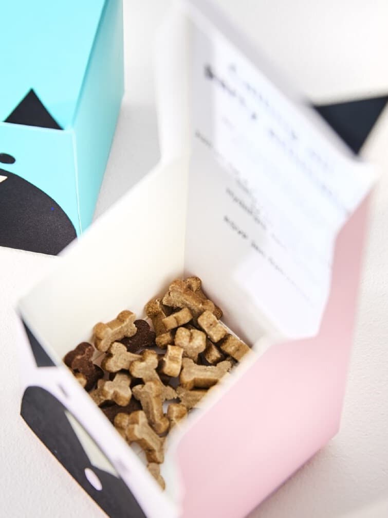 Petite boîte en papier décorée pour représenter un chien et remplie de biscuits pour chien.
