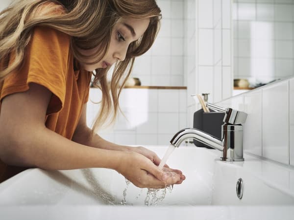 Petite fille recueillant de l'eau coulant d'un robinet dans ses mains