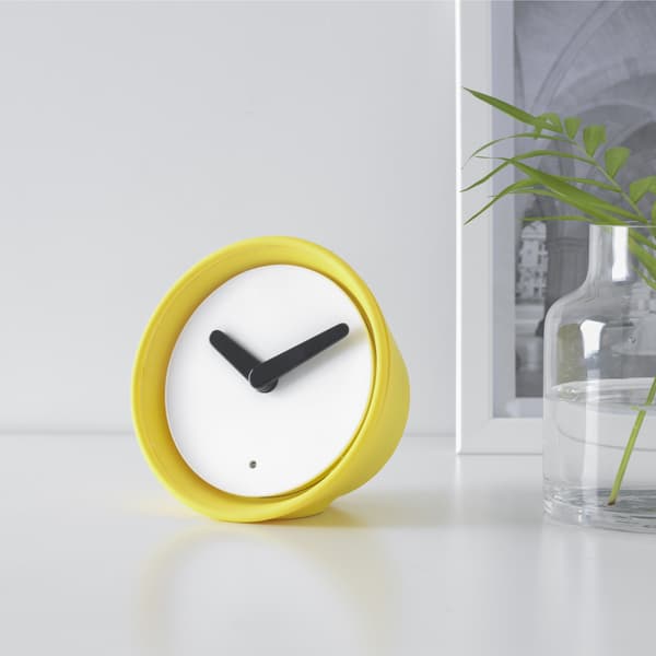 Petite horloge de table jaune sur fond blanc.