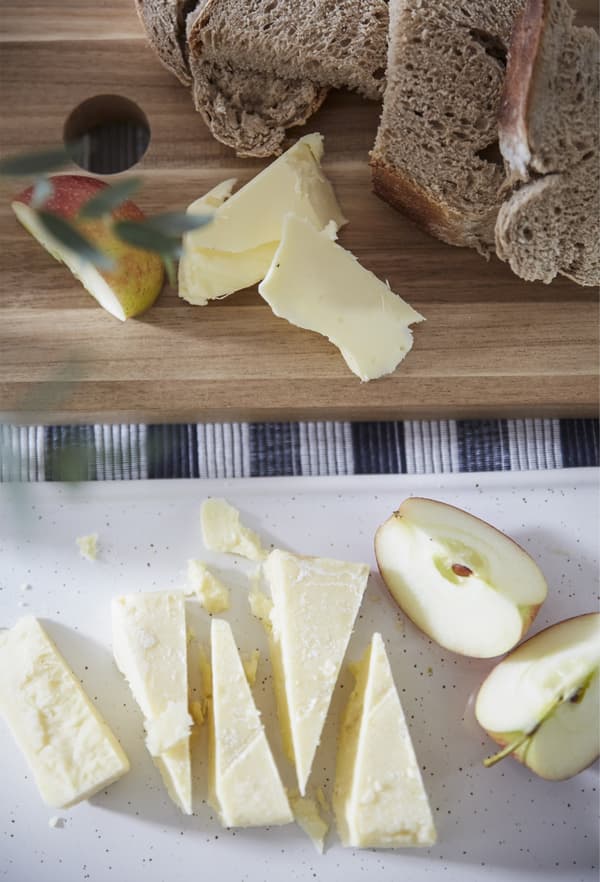 Pezzi di formaggio, mela e pane su dei taglieri.