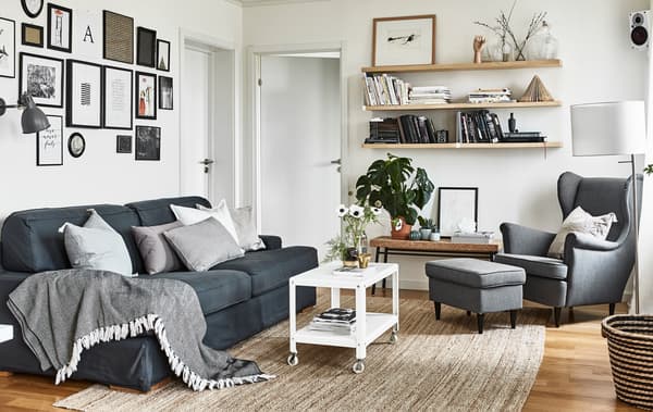 Photo d'un séjour décoré dans des couleurs neutres, avec canapé, fauteuil et étagères.