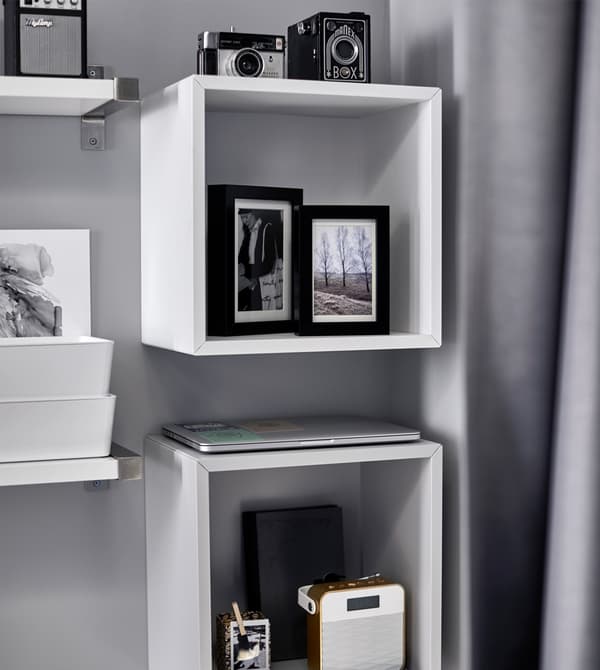 Photos, cameras, and a stereo are displayed on a shelf above a bed.
