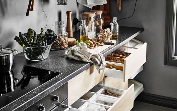 Piano di lavoro con tagliere, contenitori in vetro e alcuni cassetti aperti con frontale frassino - IKEA.