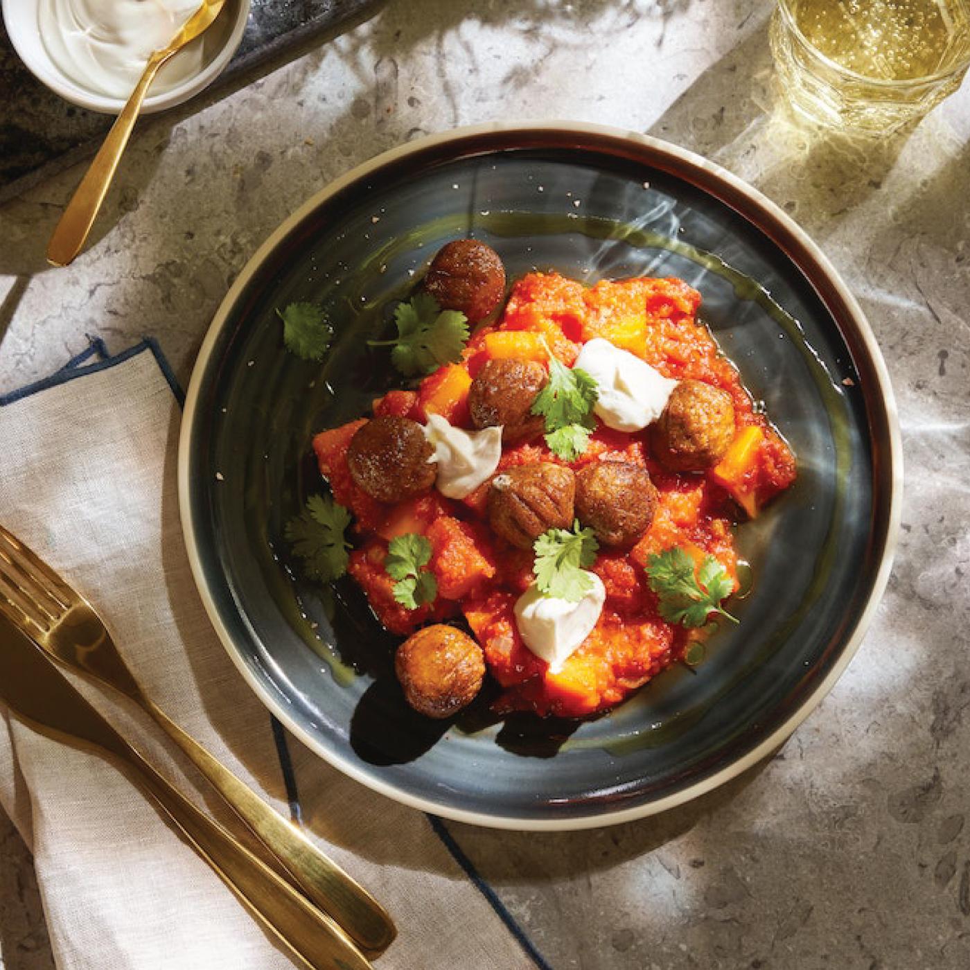 Piatto piano grigio verde con all'interno polpette svedesi su tavolo in pietra