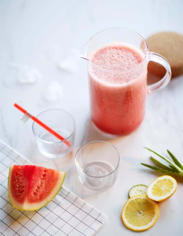 Pichet contenant un smoothie à base de pastèque et de concombre, entouré par des ingrédients.