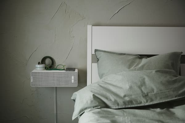 Picture of a bedroom with a speaker as a bedside table.