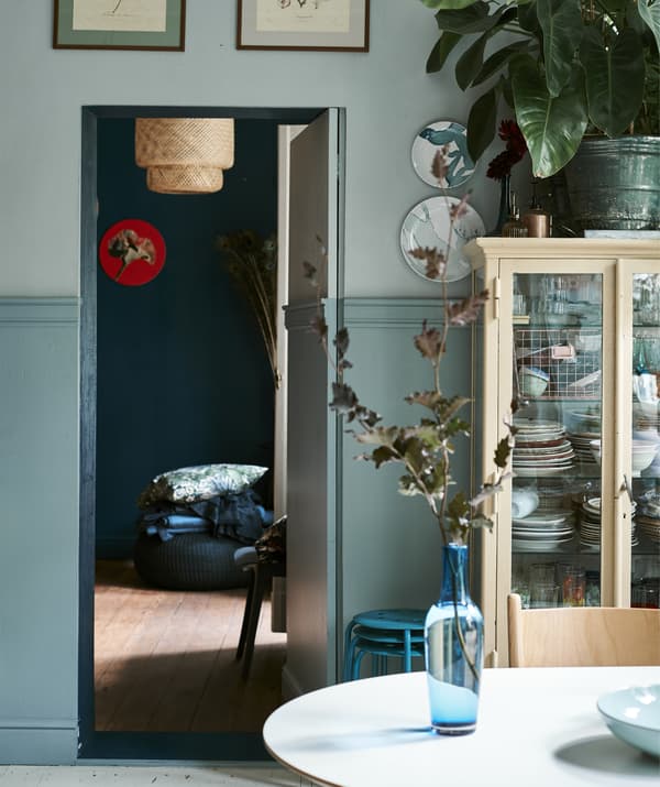 Picture of blue glass vase on a table with view into the bedroom through an open door.