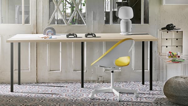 Pièce ensoleillée avec long bureau composé d’un plateau de table LAGKAPTEN effet chêne et de cinq pieds ADILS noirs.