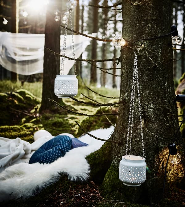 Pied d’un arbre utilisé comme dossier pour un coin ‘salon’ avec peau de mouton et coussins