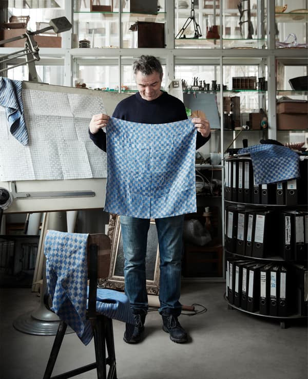 Piet Hein Eek holding up patterned blue textiles.