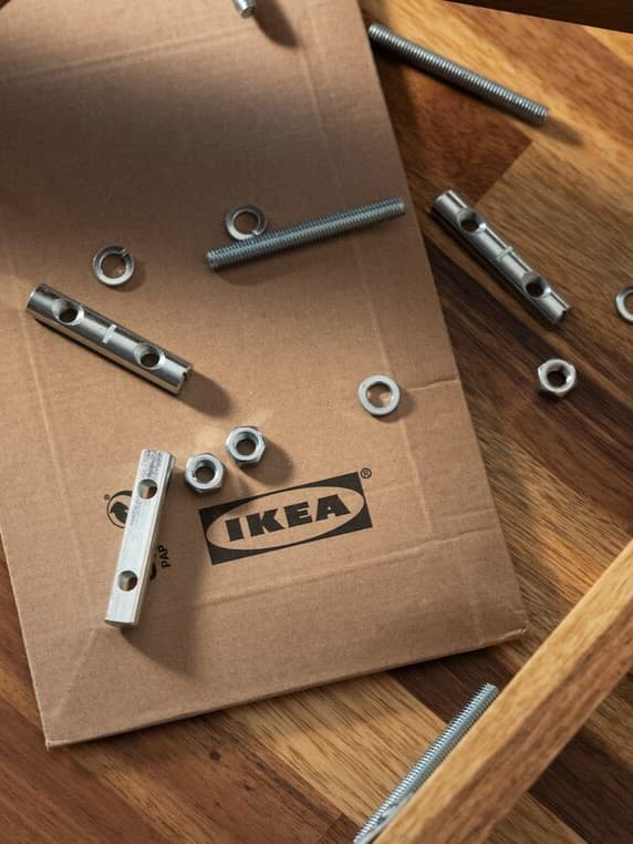 Piezas de tornilleria sobre un sobre de cartón con el logotipo de IKEA.