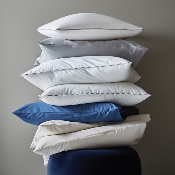 Pile de sept oreillers sur un pouf.