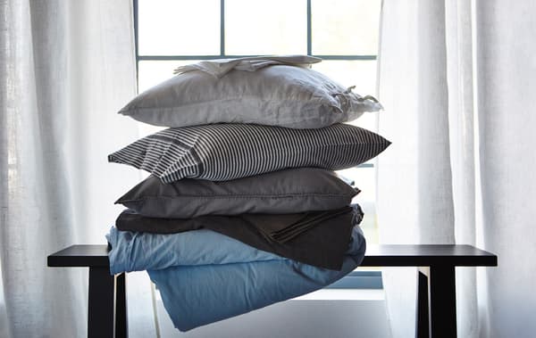 Pile d'oreillers et de linge de lit dans différentes matières qui aident à réguler la température corporelle